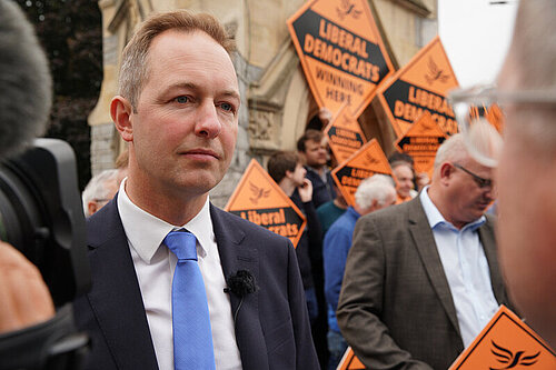 Richard Foord being interviewed in front of activists and signs reading "Liberal Democrats Winning here"