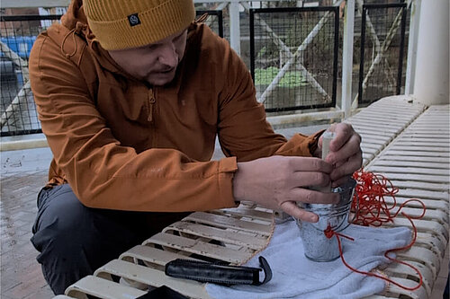 Cameron Thomas sits beside the River Avon at Tewkesbury helping to test water quality